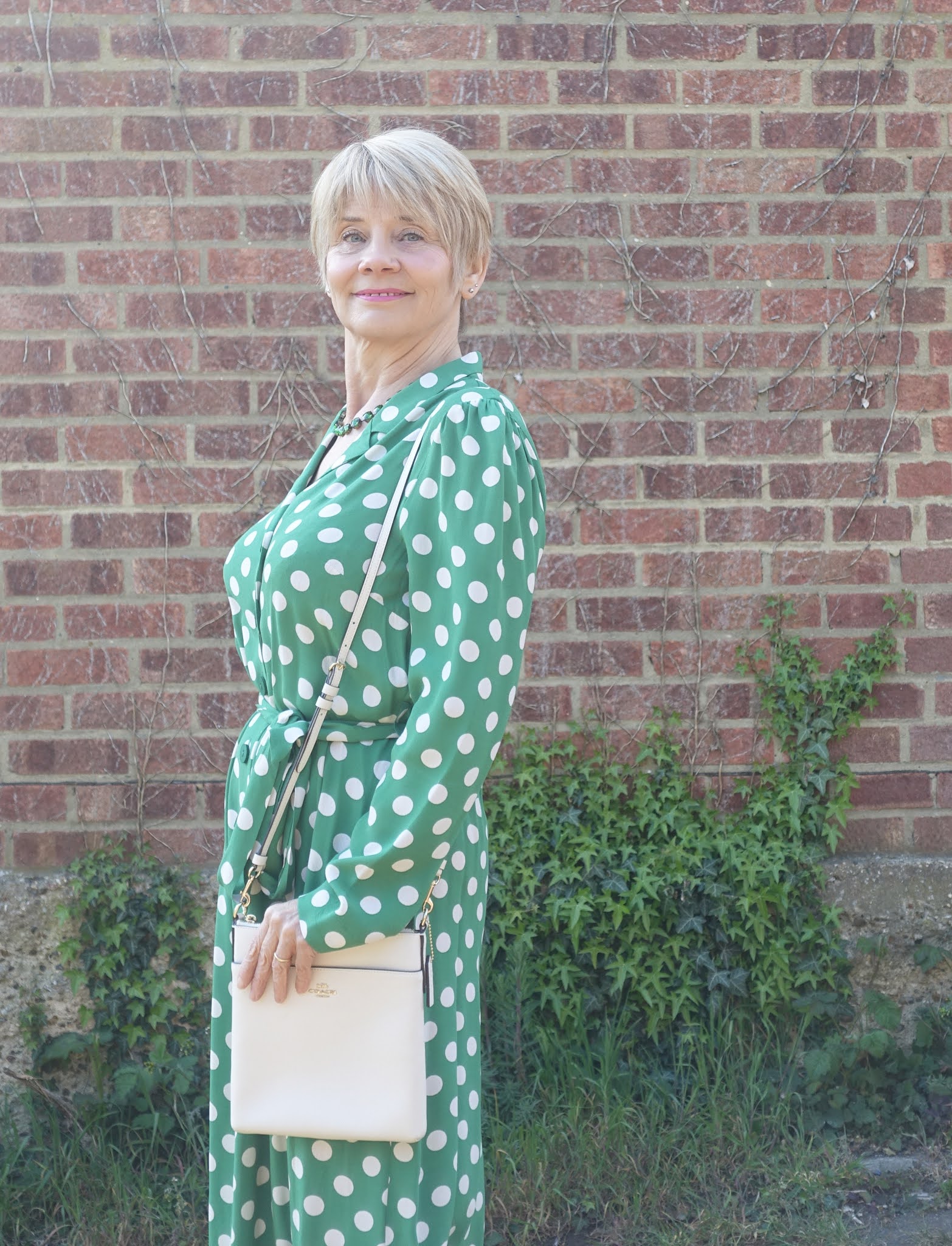 A green shirt waister dress with polka dots and belt from M&S worn by over-50s blogger Gail Hanlon and accessorized with green sequin T bar shoes from Irregular Choice