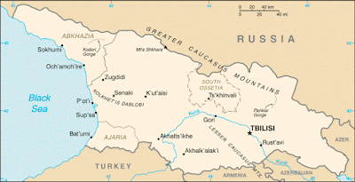 This map shows Georgia as a cream-colored area between the darker tan areas of Russia to the north and Turkey to the south. The Black Sea is represented as a blue area to the west, and Armenia and Azerbaijan are additional tan areas to the south and east. Tbilisi, the Georgian capitol, is marked with a black star in the eastern end of the country, along the Kura River.