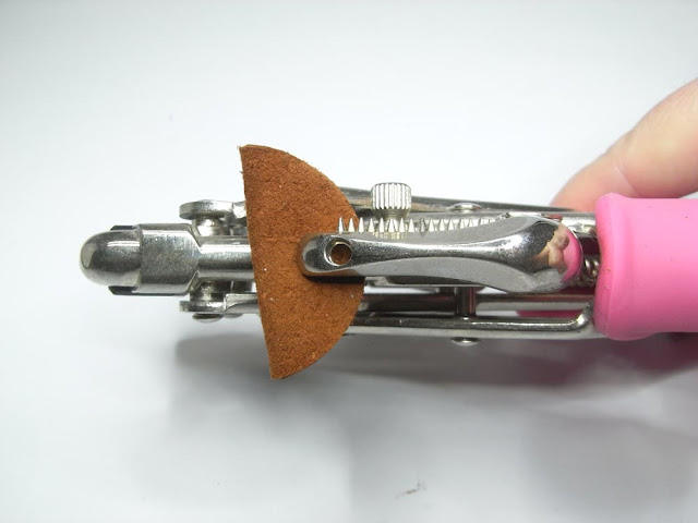 Punching a hole through both sides of the folded brown suede circle