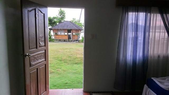 view of the outside garden and a nipa hut day-use cottage from the dormitory room of EWP Island Beach Resort in San Antonio, Dalupiri Island, Northern Samar