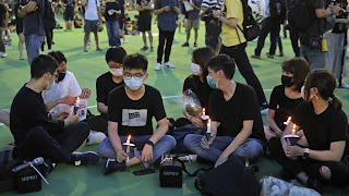 In this June 4, 2020 photo, Hong Kong democracy activist Joshua Wong, second left, holds candle as he joins others for a vigil to remember the victims of the 1989 Tiananmen Square Massacre at Victoria Park in Hong Kong- Photo Credit- AP