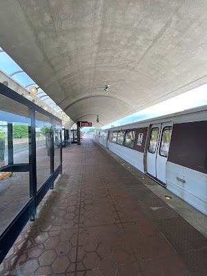 Photo of a Metro platform with an arched roof and a train idling.