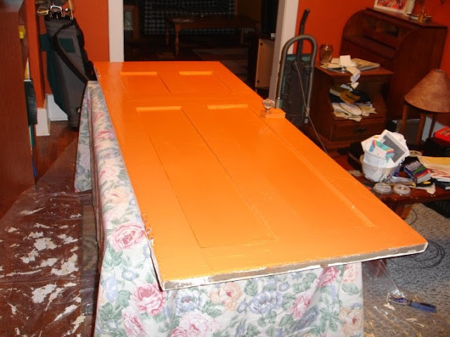 Orange bathroom door being painted on a table.