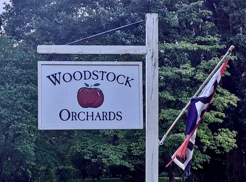 A sign that reads "Woodstock Orchards" and a red, white, and blue flag that reads "Open"