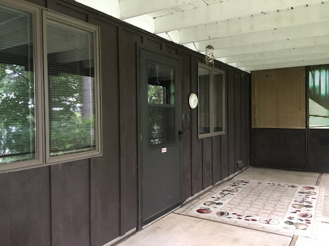 central Minnesota lakeside cabin home with dark exterior board and batten and screened in porch