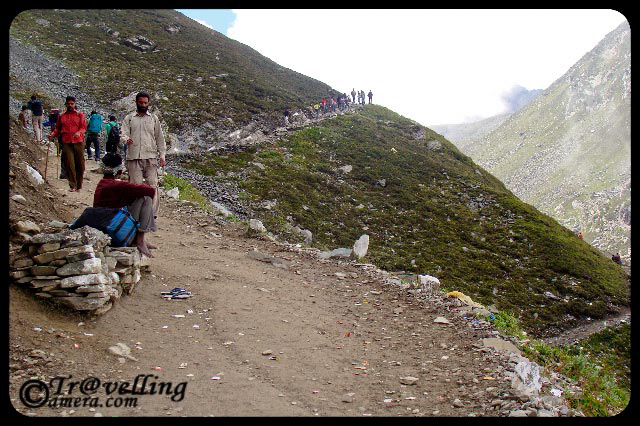 Typical Trekking routes on the way to Manimahesh Yatra in Himlayas (Pir Panjal Mountain ranges) : Part-2 : Posted by VISHAL SHARMA on www.travellingcamera.com : Continuing the PHOTO JOURNEY through various treks to Manimahesh, here are few more photographs on the way to Manimahesh Pilgrimage Yatra in Chamba District of Himachal Pradesh...Check out Part-1 if you have missed itNow clouds have starting chasing us and it can be a bad sign for such treks... Since trees will not be there on these heights, there will be no space to escape if rains start... If there is no rain, journey becomes wonderful with these clouds... because you will never know how much you have to cover next :-)Some of us had some tents so we were comparitively safe if rain would have started... Here is a again a view of valley in the bottom of two hills with tents... Many of the pilgrims were looking back after some time... clouds were becoming more dense as we moved ahead...Other worry was the path... since it was soil and stones... after rains it becomes risky to walk over them... If you are first time trekkking on hills, its important to have nice shoes with appropriate grip and have to have pateince to walk on the a balanced pace to avoid any mishappening... Don't worry, I was getting more sensitive about it.. Plan better and its very easy :-)Here is an amazing this... See this path started form hill on right side and moved towards the another hill on left which is just opposite to the first one... But everyone had to cross through the same route, because the riverlets you see in the middle had very fast current... which is not very clear in this photographs.. but if  you compare the size of tents and width of this strea, you would be able to estimate it... This whole path  from one hill to another was around 4-6 kms....Here comes the next level of tis trek with more rocky hills around and less grass.. Indicating that oxygen level is going down now.... Check out the photograph above and try to find out the path we followed.. Similarly, in this photograph its not very easy to locate the path... One is short cut and other one is long but smooth... Imagine yourself on this trek and huge moutains around... Can you see a large group of pilgrims on the turn?? Imagine the size of these hills... I can't explain...Pilgrims taking rest on the way to Manimahesh Lake in Bharmour region of Chamba District in Himachal Pradesh...People who can't walk upto the hills and don't want to ride in Helicopter have another option... Horse Riding  @ Mani Mahesh, Chamba, Himachal Pradesh, INDIA