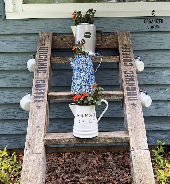 Photo of a ladder decorated with an Organic Coffee stencil, coffeepots with impatiens, and coffee cups