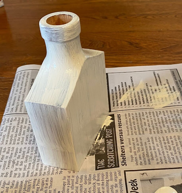 Photo of a small wooden flask being painted white.
