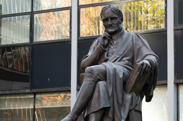 Statue of seated John Dalton with book in left hand