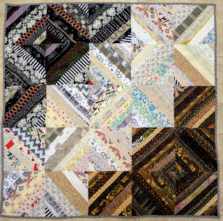 Scrap quilt of diagonal fabric strings in black, brown, and white.