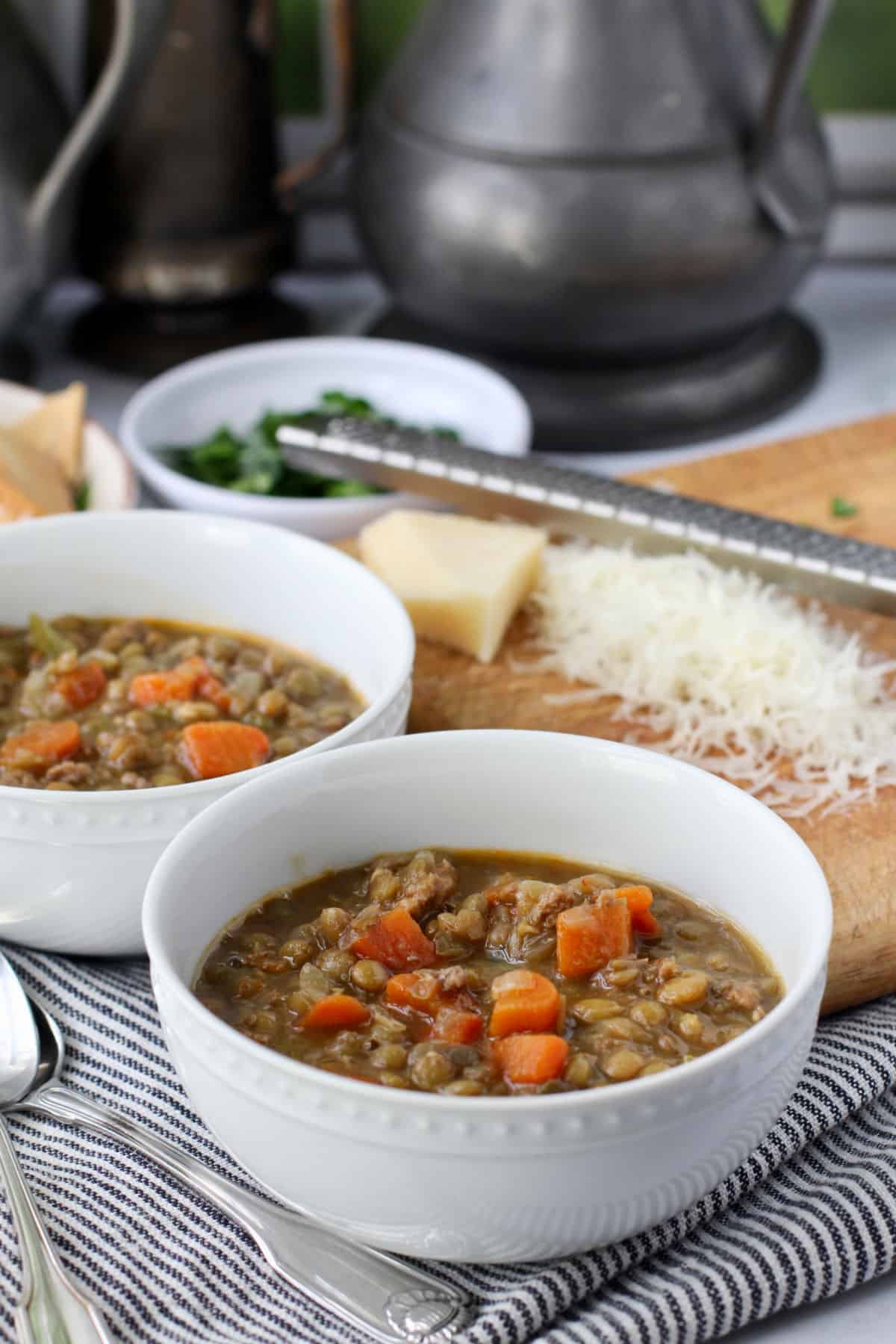 Spicy Turkey Sausage and Lentil Soup in bowl with a cheese grater on the side.