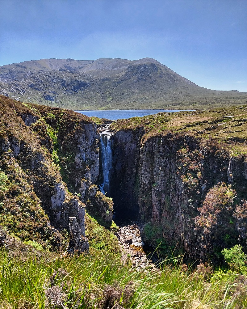 View of wailing widow falls with loch and hills in background