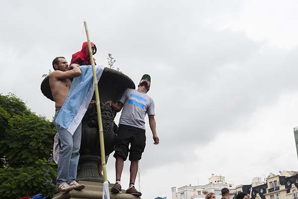 tres personas subidas a un monumento con una bandera argentina