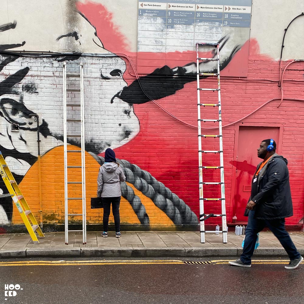 French street artist Zabou at work in the rain on her latest London mural