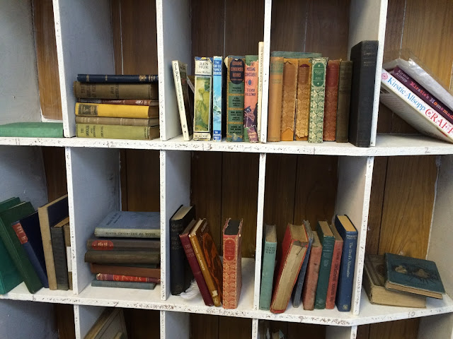 white bookshelves with various bundles of vintage books in each shelf