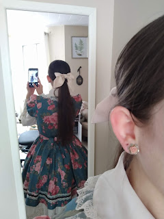 A photo of my reflection. I am facing away from the mirror so that you can see a bow on the back of my head. I am wearing Marie Rose dress by Innocent World