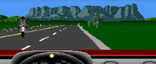 Shows a Road rash style of game display with black motorbike guy on road with green around the race track and on the mountain back grey coloured and on the bottom of the screen see whell and also red to represent top of the car dashboard