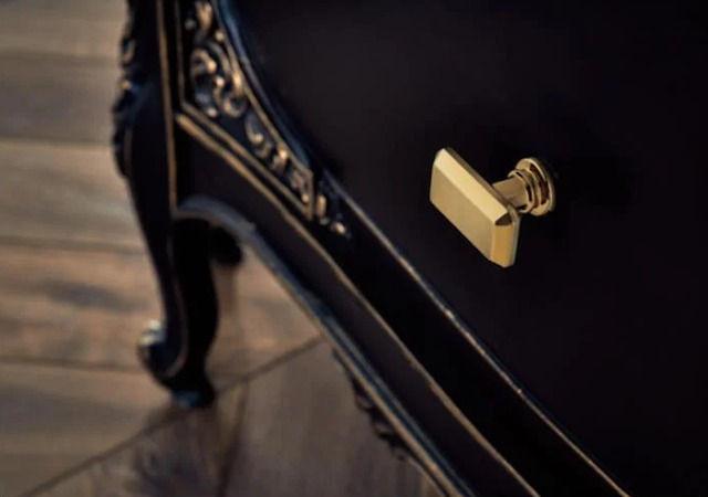 Black vanity with gold cabinet drawer knob.