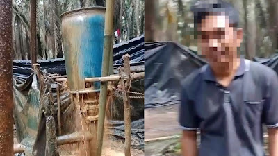Lokasi yang diduga sumur minyak ilegal di wilayah Hindoli, Kecamatan Keluang, Musi Banyuasin, terlihat alat penyulingan tradisional dengan drum biru dan aliran cairan pekat; seorang pria yang diduga Tegu Susanto, Ketua BPD Desa Sungai Batang, tampak berdiri di dekat lokasi.