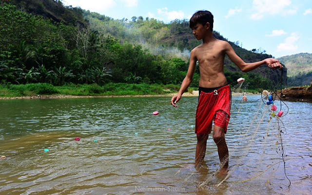 Anak warga setempat sedang menjaring ikan di Sungai Oya