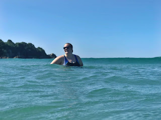 Image of a plus sized woman standing in the water at the beach: This article is about Swimming For Weight Loss