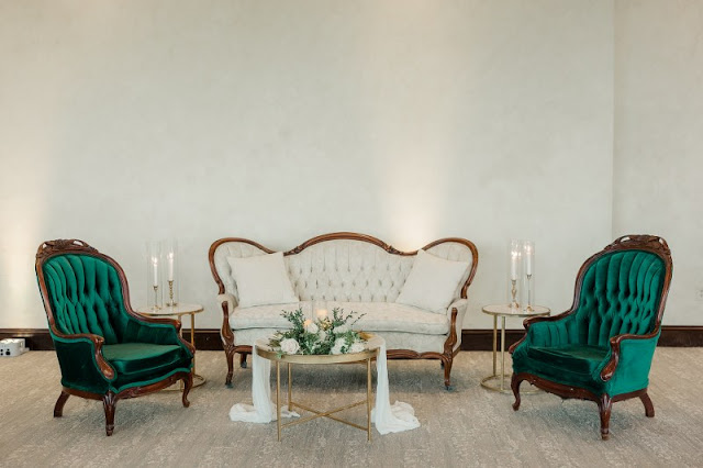 lounge area with white and gold sofa and emerald green armchairs