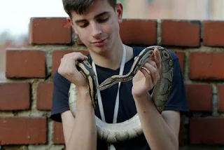 A young man handling his pet snake.