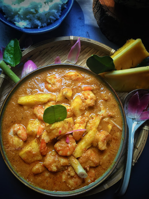 "A vibrant bowl of Nyonya Prawn Curry with Pineapples, garnished with fresh herbs and slices of torch ginger flower, showcasing the rich colors and textures of this traditional Peranakan dish."