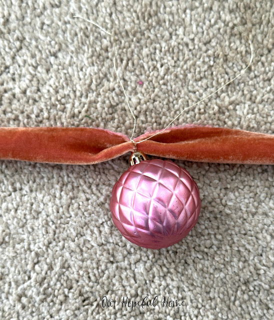pink quilted pattern Christmas ornament tied onto velvet ribbon with gold string