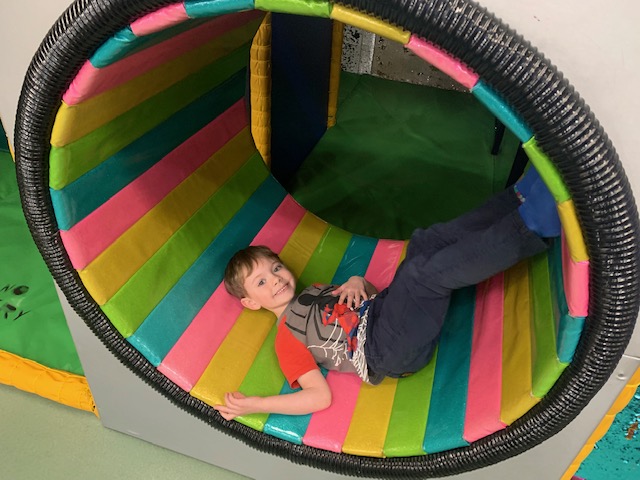 Boy in a rainbow striped hamster wheel-style chair
