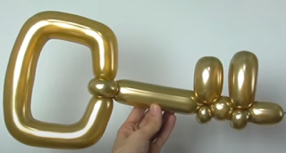 Goldener Schlüssel als Ballonmodellage aus einem Modellierballon.