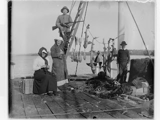 family group on jetty - woman sitting knitting while kids catch fish