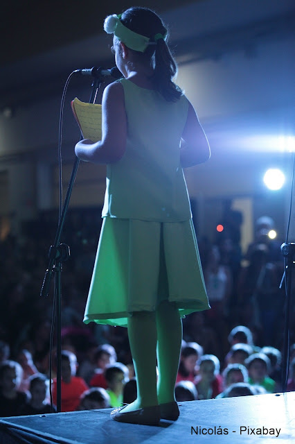 Menina num palco recitando poesia.