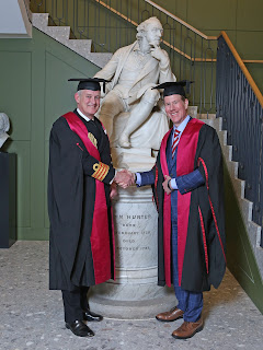 Dr. Eric Elster, dean of USU's School of Medicine (right) and Surg. Capt. Rory Rickard, Assistant Head (Research) and Emeritus Professor of Military Surgery, pose in front of the statue of John Hunter, the founder of 'modern' surgery from the 1700s, at the Royal College of Surgeons of England.