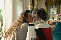 two women kiss while a third woman stands behind