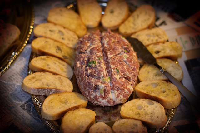 A brain shaped cheese ball with little toasts around it. 