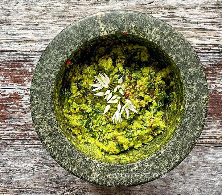 Recipe for how to make wild garlic pesto. Wild garlic pesto pictured in a pestle and mortar.