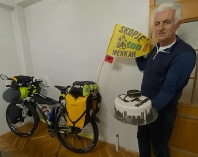 Qamuran Hirda in Skopje with a cake in his hand and his bicycle by his side a few hours before leaving for Mecca