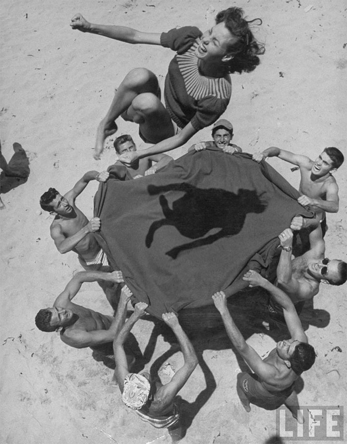 60 Inspiring Historic Pictures That Will Make You Laugh And Cry - Teenaged Boys Using Blanket To Toss Their Friend, Norma Baker, Into The Air On The Beach, 1948