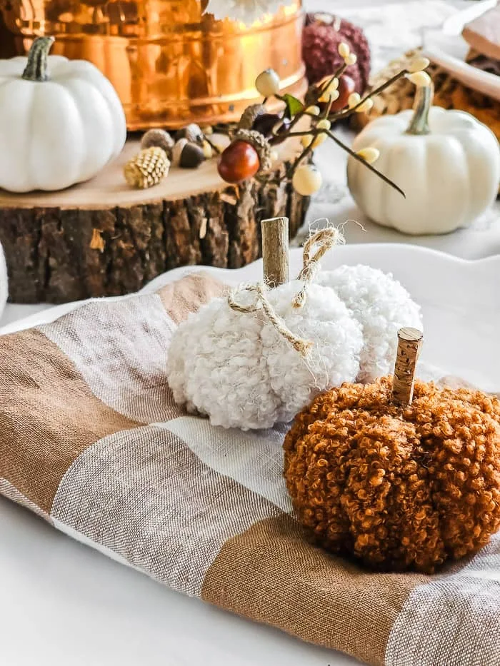 white and brown Sherpa pumpkins, brown plaid linen napkin, wood slice