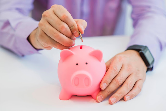 Un señor introduciendo dinero a una alcancía de cochinito haciendo referencia al habito del ahorro