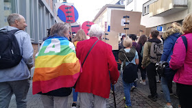 Eine elegant gekleidete Frau wird von einer Vertrauten gestützt und läuft am Stock in der Demo mit