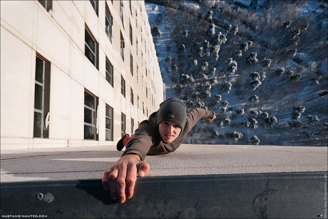 Man hanging on the wall with one arm