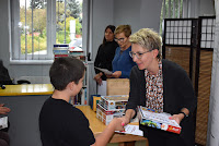 Pracownik Biblioteki Aneta Kasprzykowska wręcza dyplom i nagrodę laureatowi konkursu.