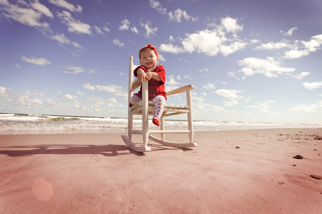 A baby sits in a rocking chair at the beach in Florida. 