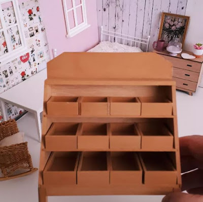 One-twelfth scale miniature green grocer's display rack held in front of a cottagecore bedroom in progress.