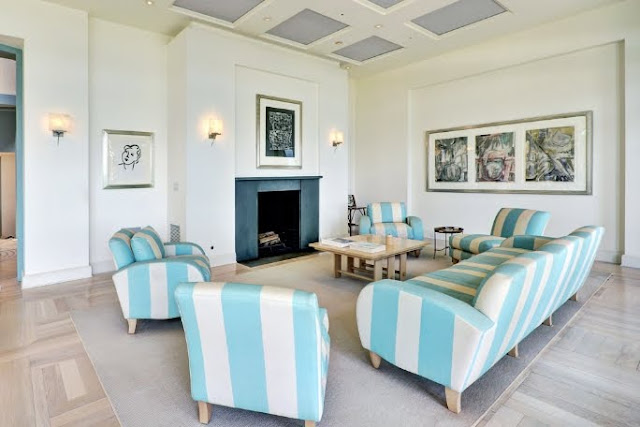 living room with high coffered ceilings, fireplace, blue and white striped sofas and armchairs and wood floors