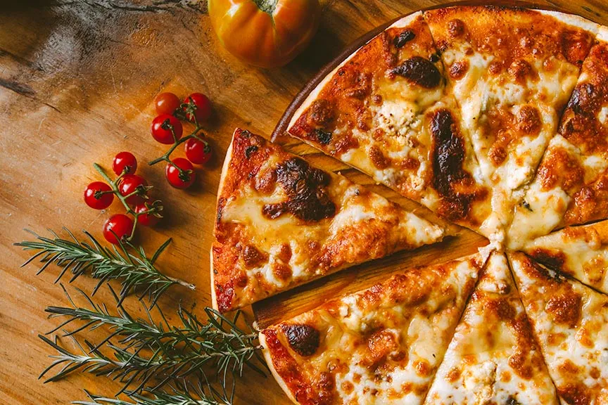 A large pizza pictured with tomatoes and rosemary.