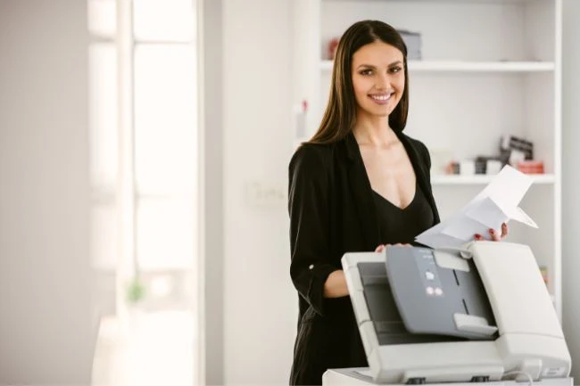 Mulher trabalhando ao lado de uma impressora para escritório