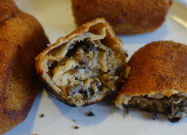 Little parcels of rolled up pancake covered in golden bread crumbs with a chopped up mushroom filling